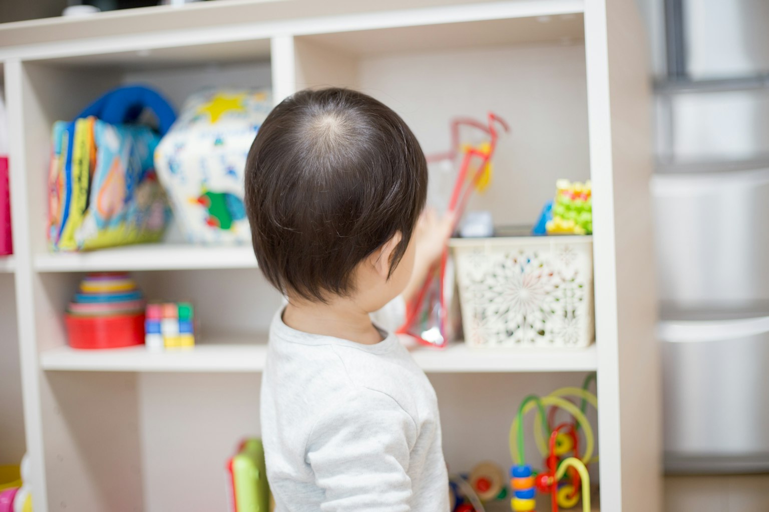 Child looking at a toy shelf from behind