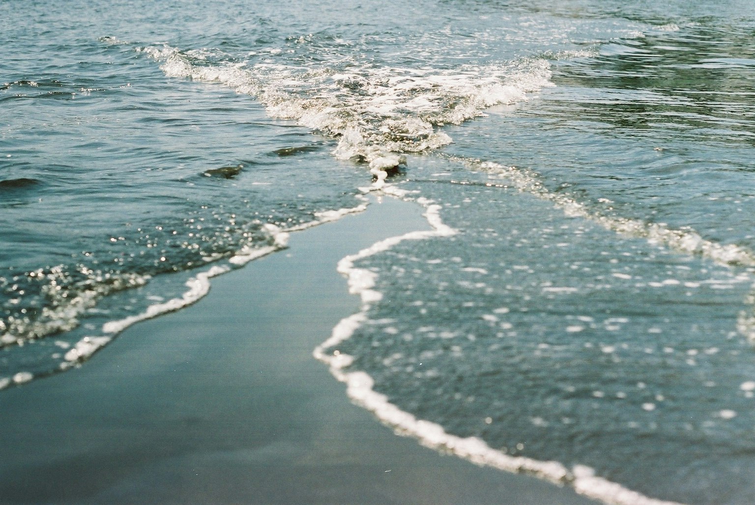 คลื่นทะเลสงบซัดเข้าหาชายหาดทราย