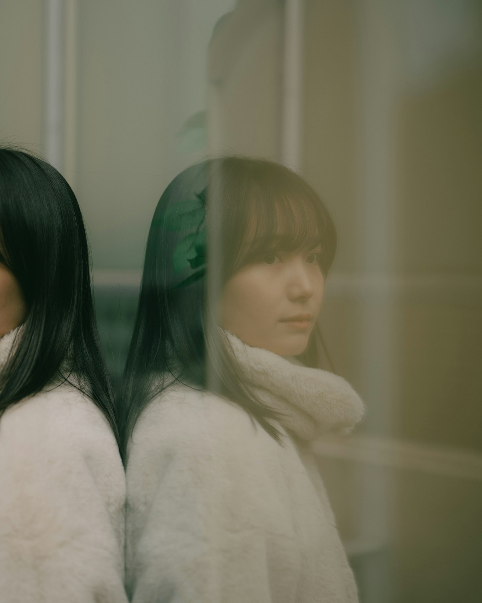 一名女性站在雙層玻璃後面，表面反射