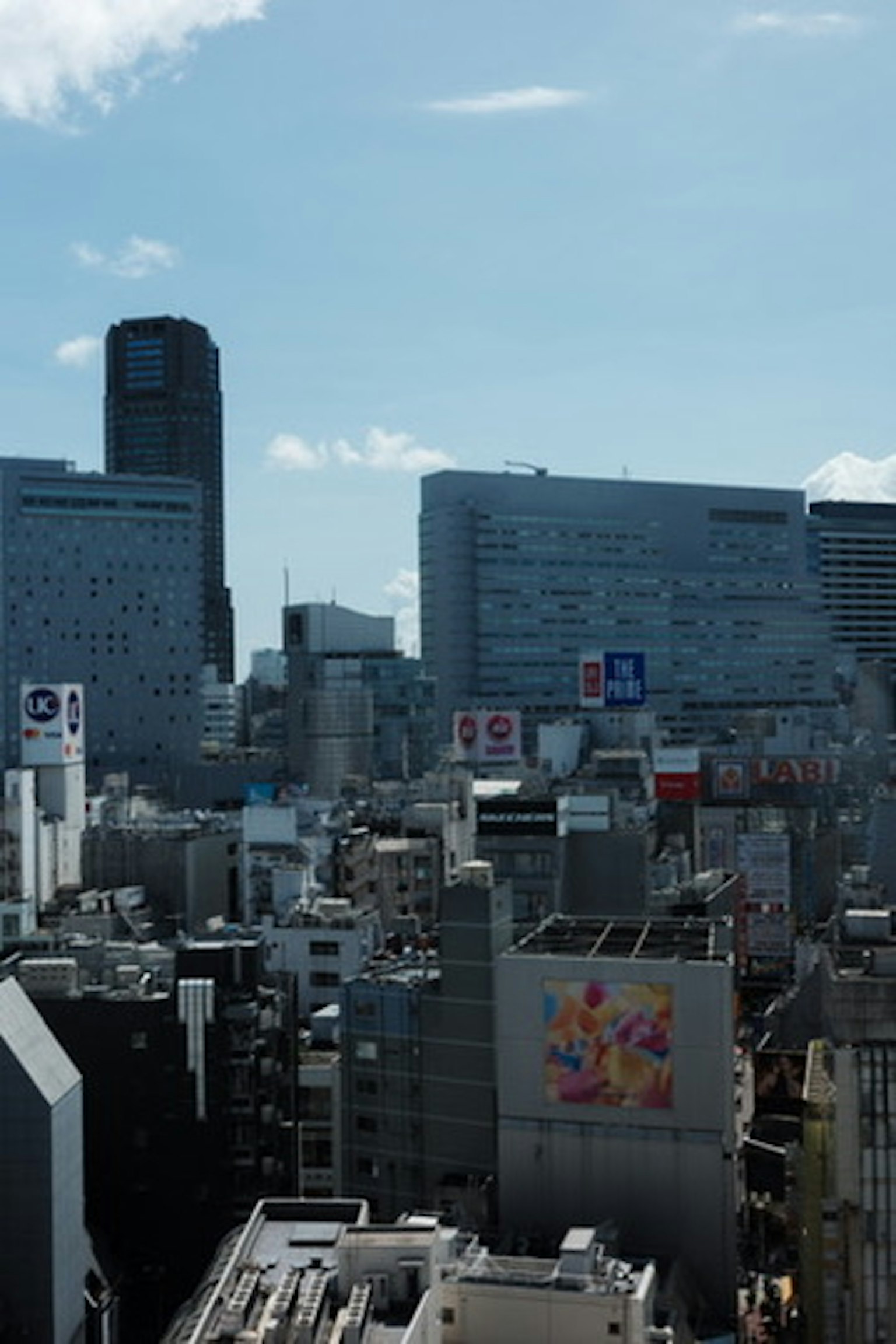 ทิวทัศน์เมือง อาคารสูงและท้องฟ้าสีฟ้าใสพร้อมป้ายโฆษณามากมาย