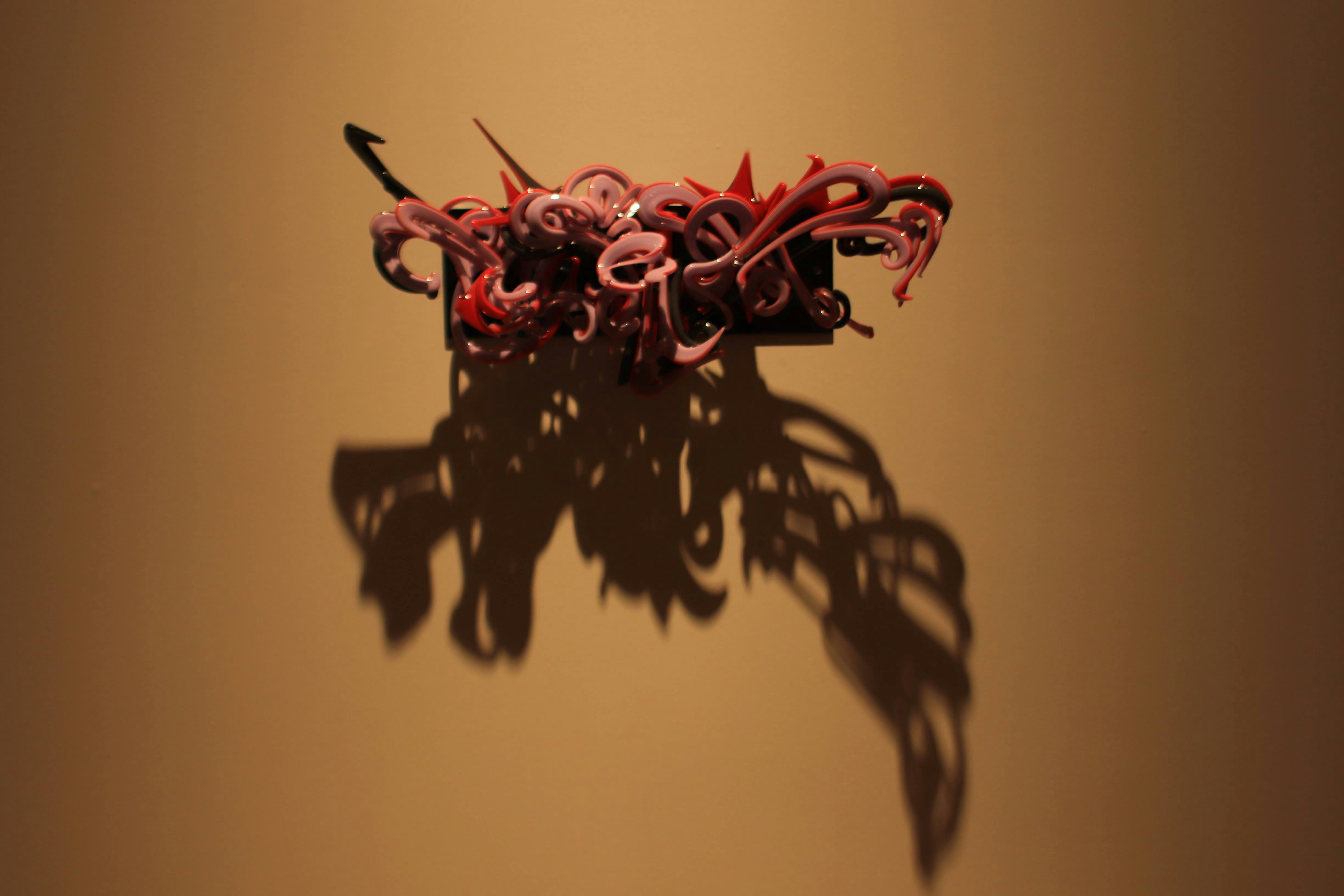 Close-up of abstract ink drips with red threads and dark shadows