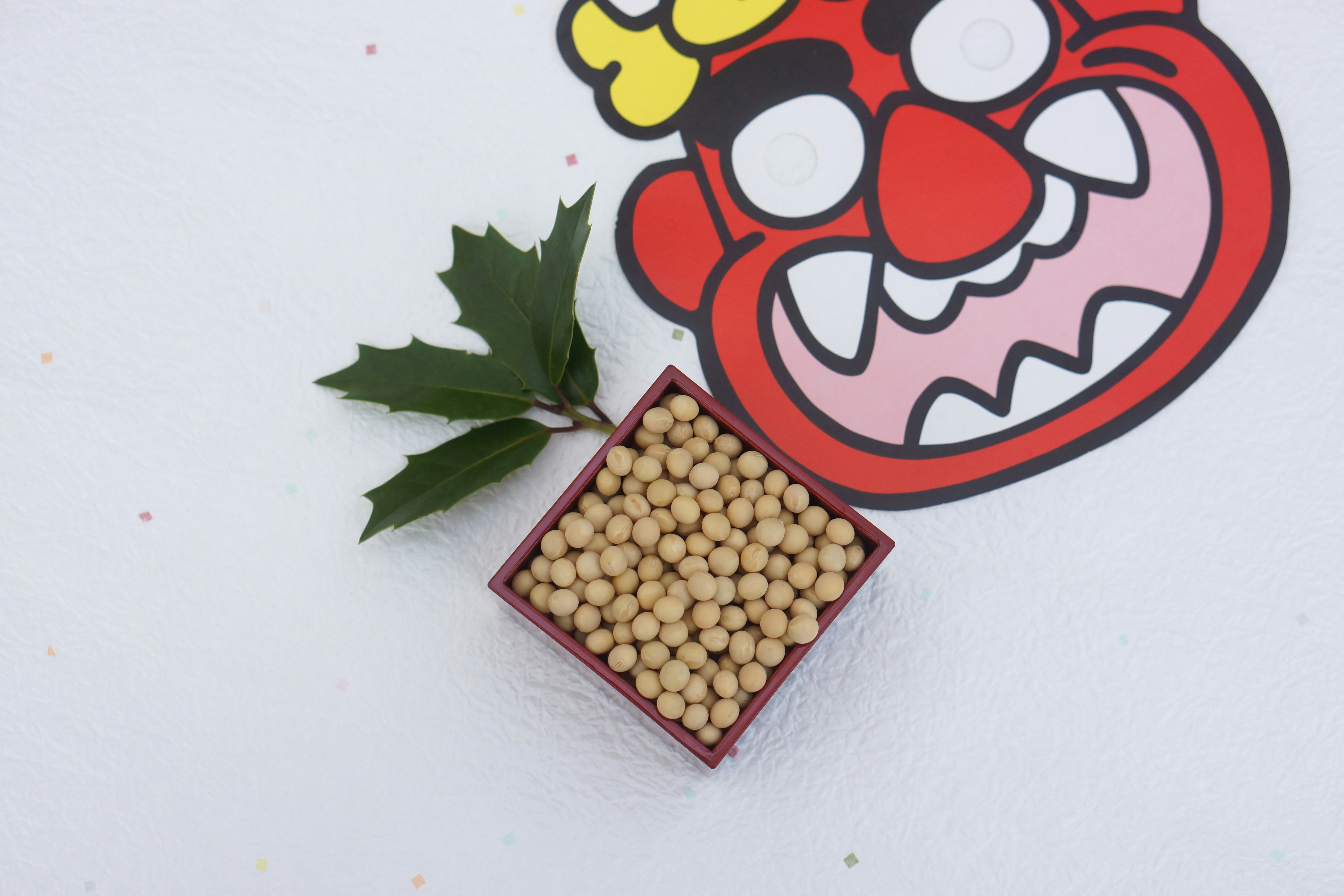 豆まき用の大豆と鬼のイラストのある白い背景