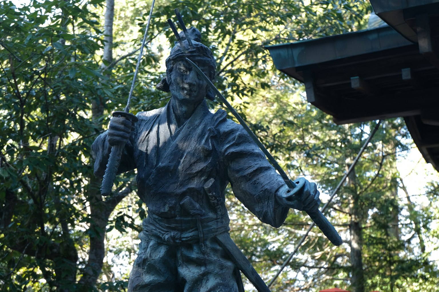 Una estatua de un samurái sosteniendo una espada en un entorno natural