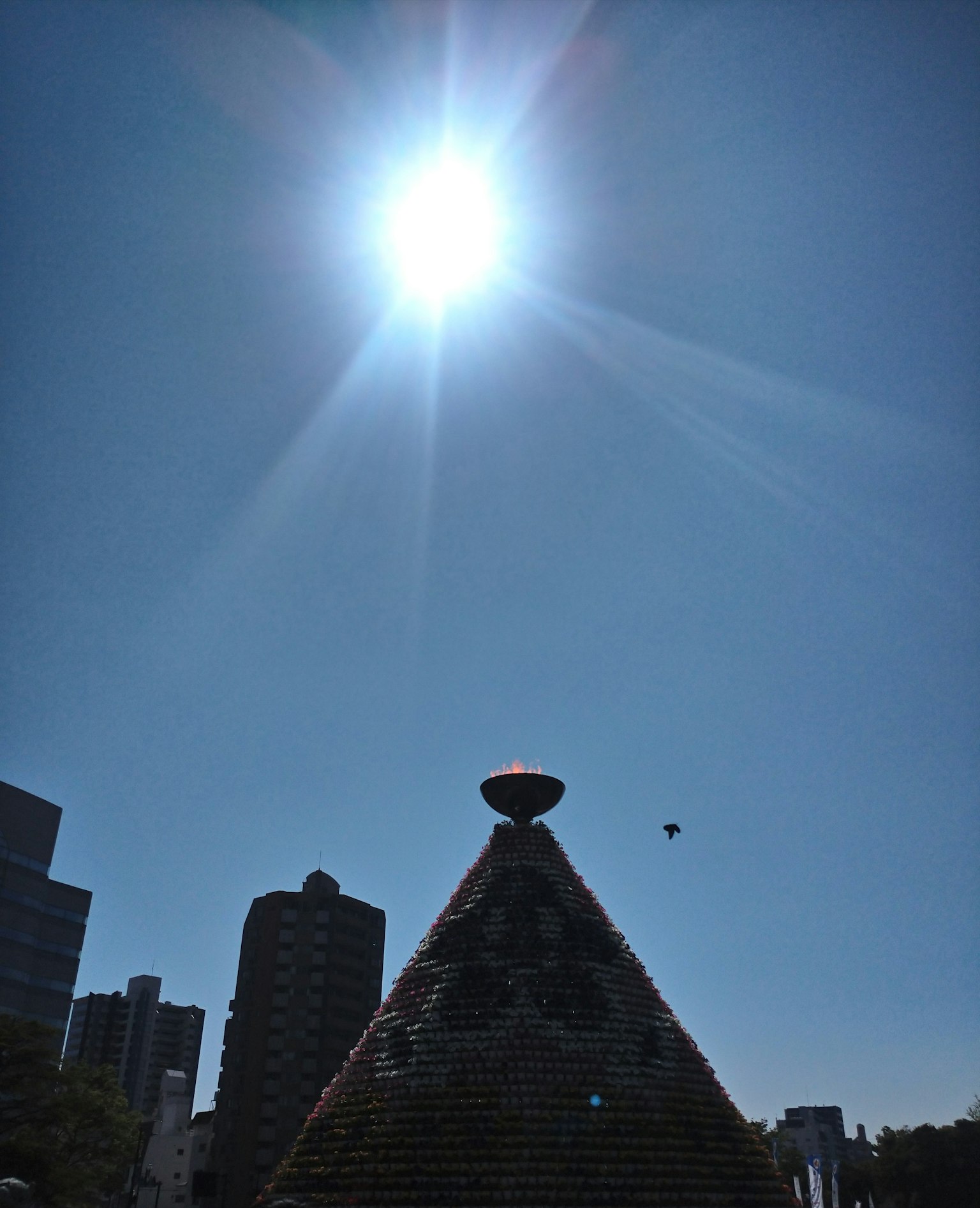 Monument en forme de pyramide sous un soleil éclatant avec des gratte-ciels en arrière-plan