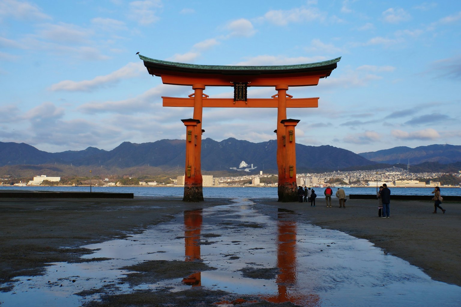Hermosa vista de un torii junto al mar con montañas de fondo
