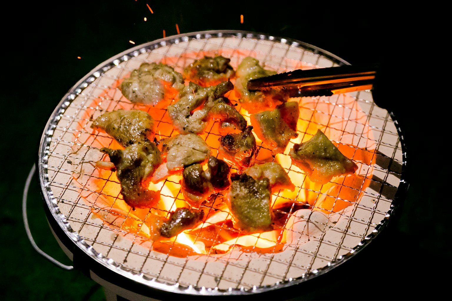 Grilled food on a charcoal grill with sparks