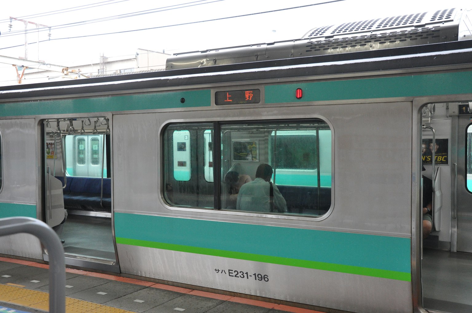 Kereta perak dengan garis biru berhenti di stasiun