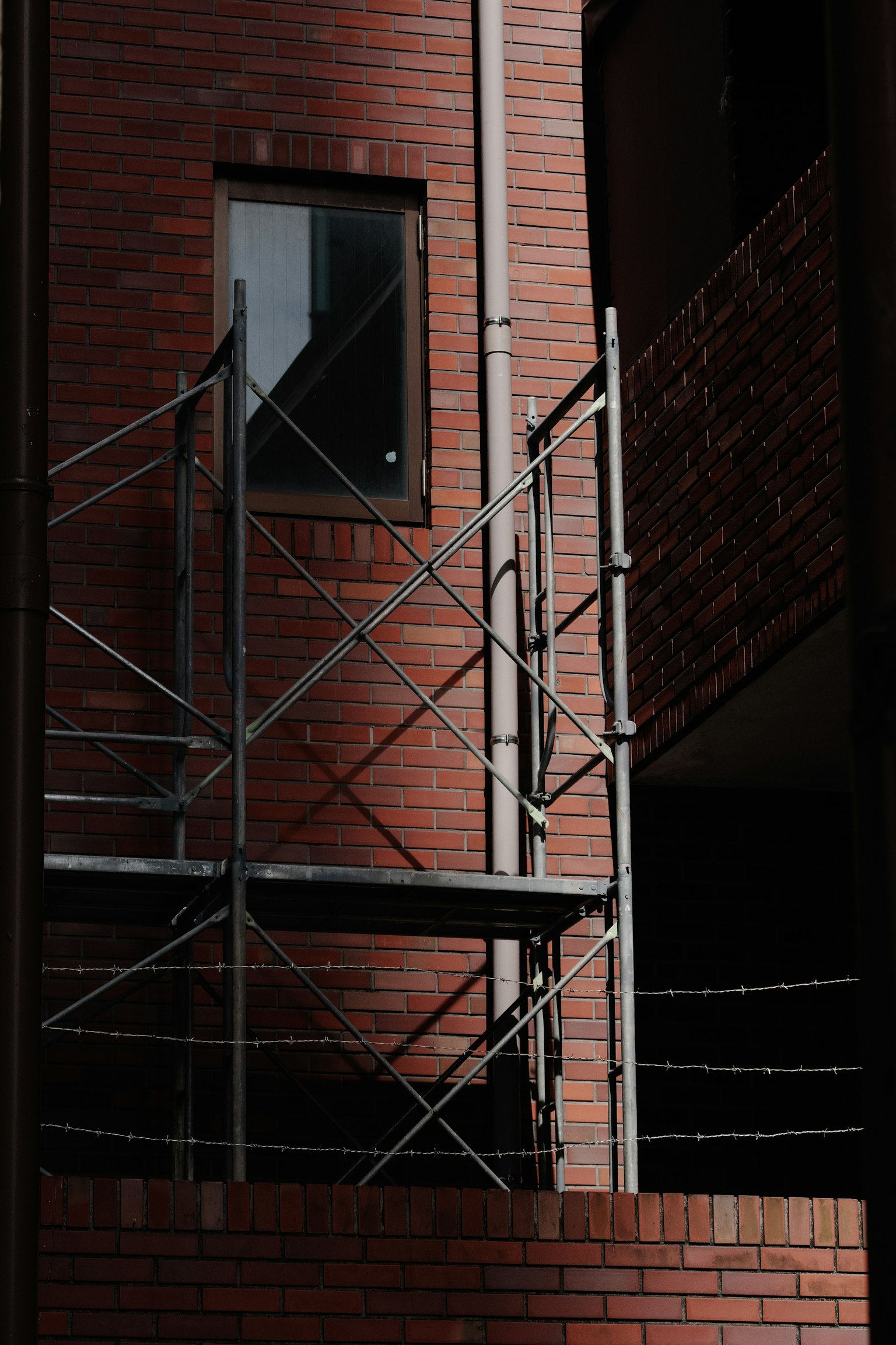Imagen que muestra un edificio de ladrillo rojo y un andamio de metal