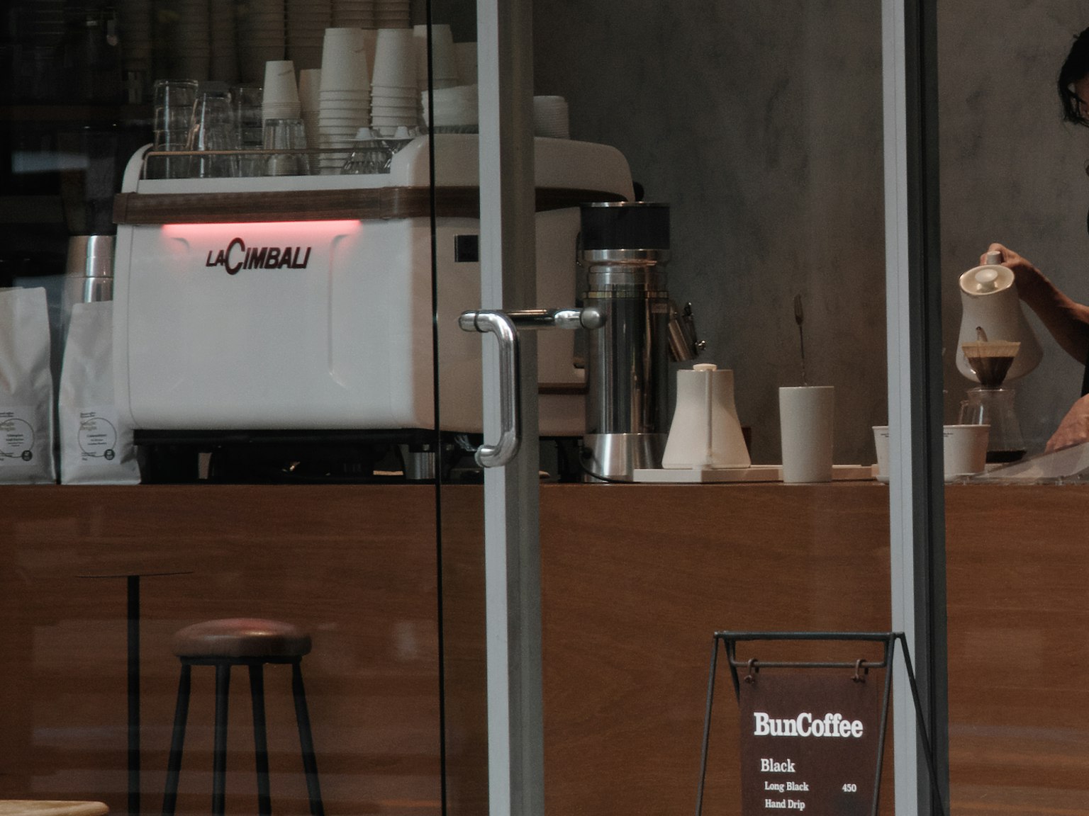 เคาน์เตอร์กาแฟที่มีเครื่องเอสเพรสโซและบาริสต้ากำลังเทกาแฟ