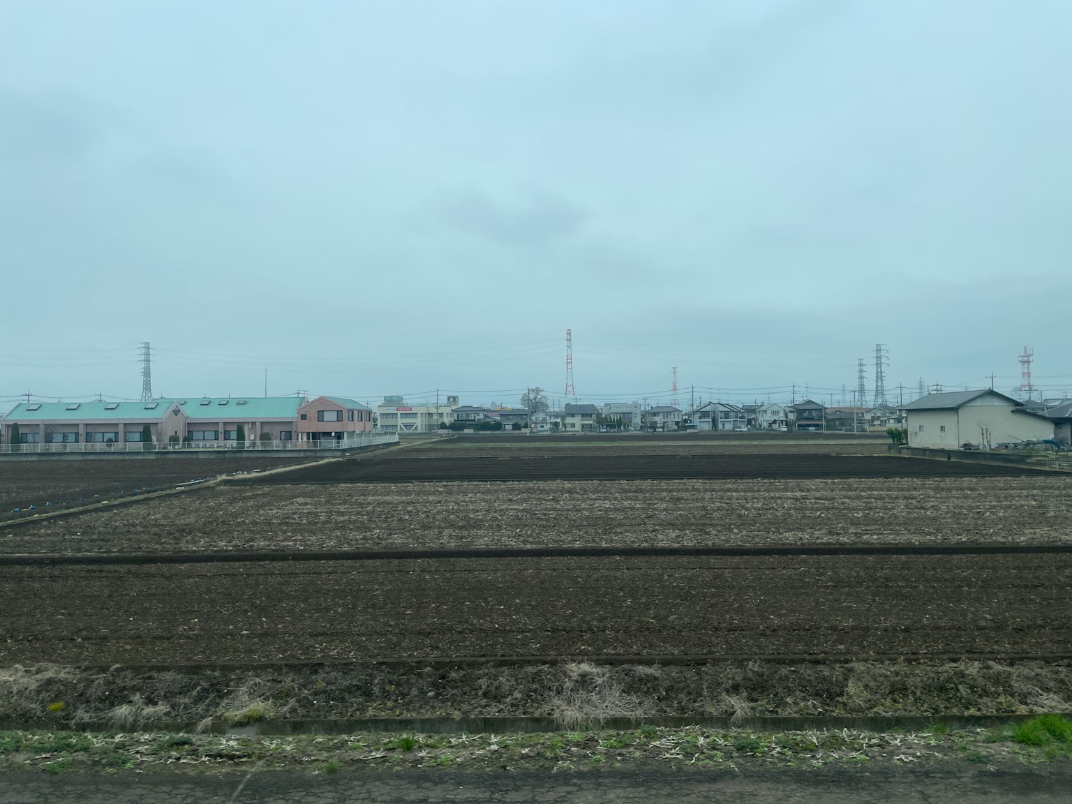 Landscape of farmland and houses under a cloudy sky