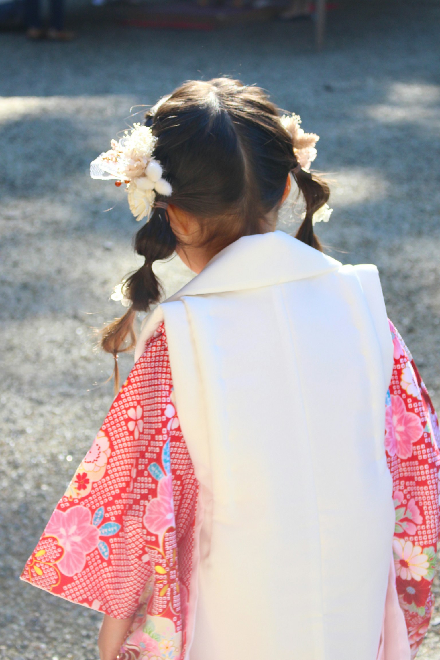 A girl in a traditional kimono with a floral hair accessory seen from the back