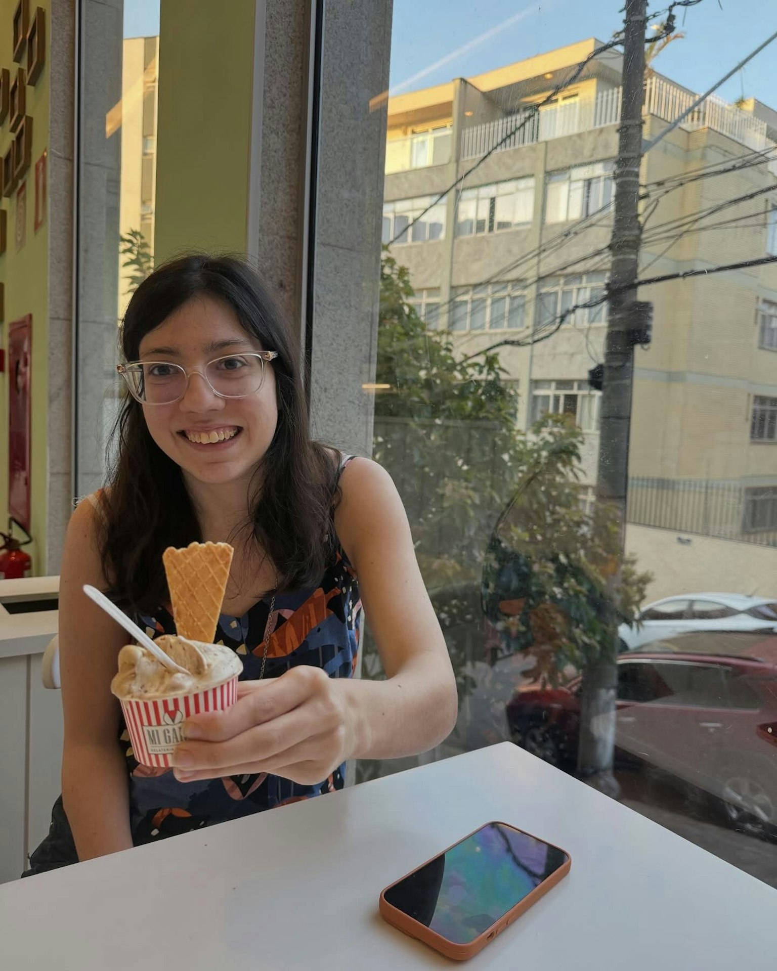 アイスクリームを持つ女性が窓際に座っているカフェの内部