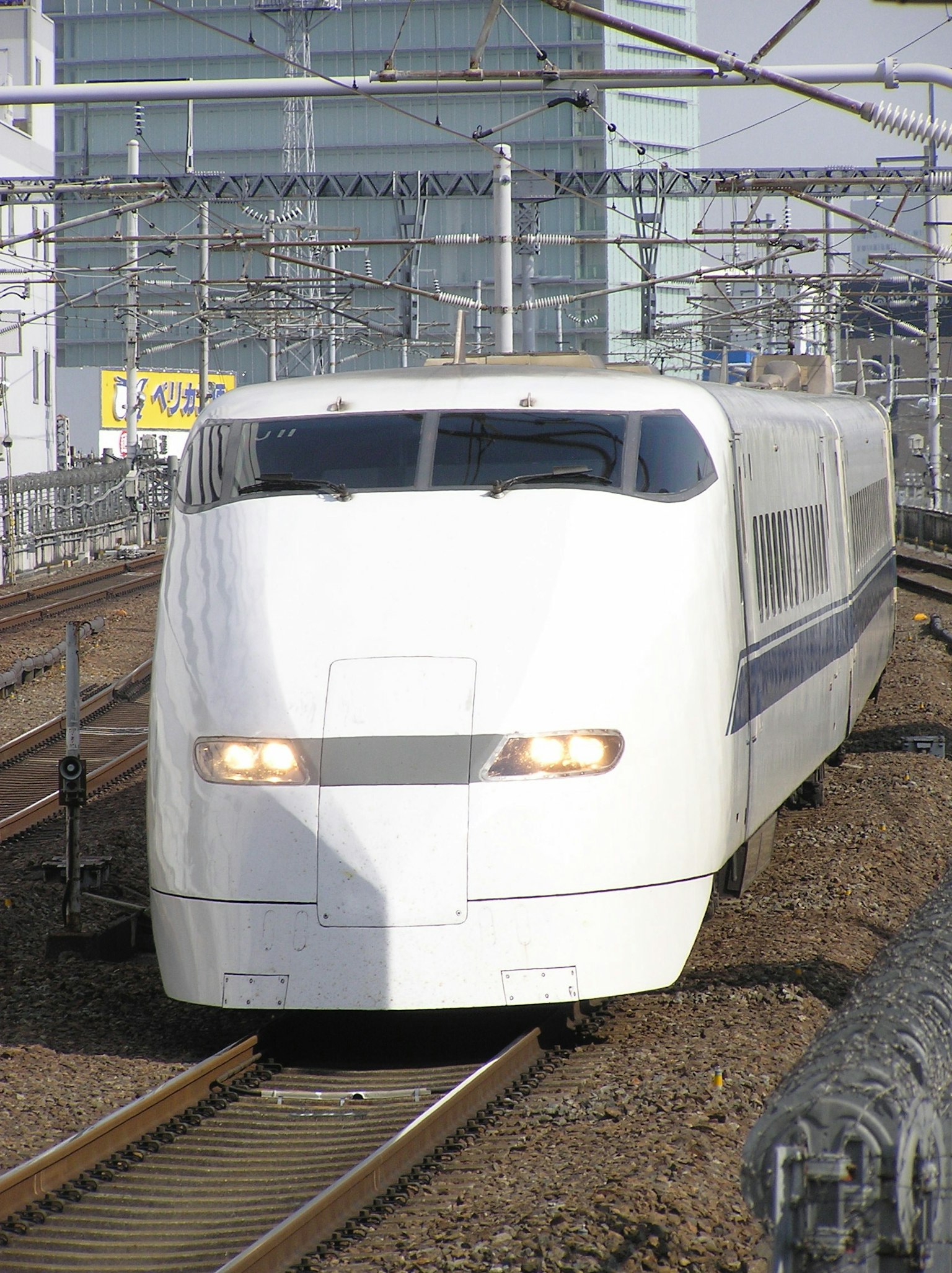 Tàu Shinkansen màu trắng trên đường ray với nền hiện đại
