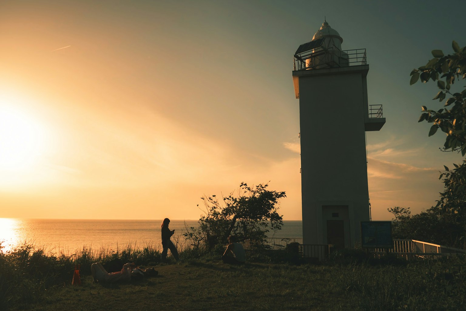 Lighthouse silhouette against a sunset over the ocean