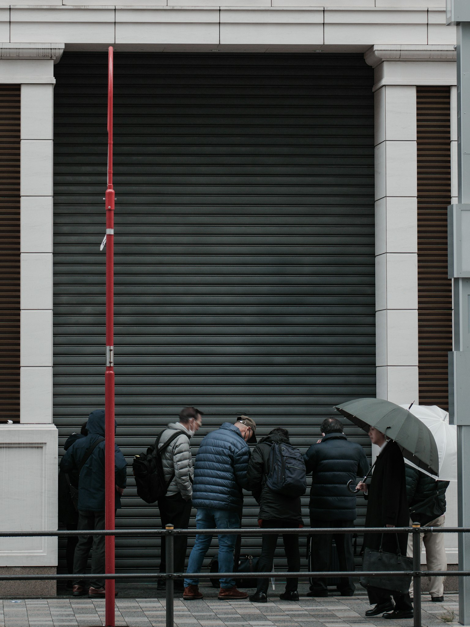 A group of people gathered in front of a closed shutter