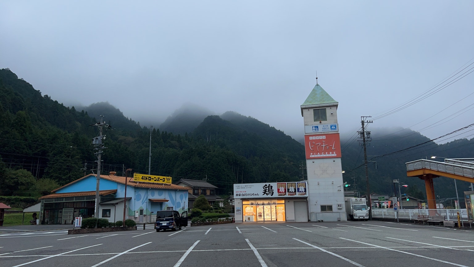 Parcheggio tranquillo con un edificio e una torre dell'orologio circondati da montagne e nebbia