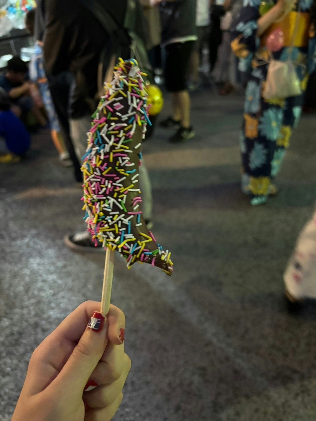bastoncino di caramelle colorate tenuto in mano in strada