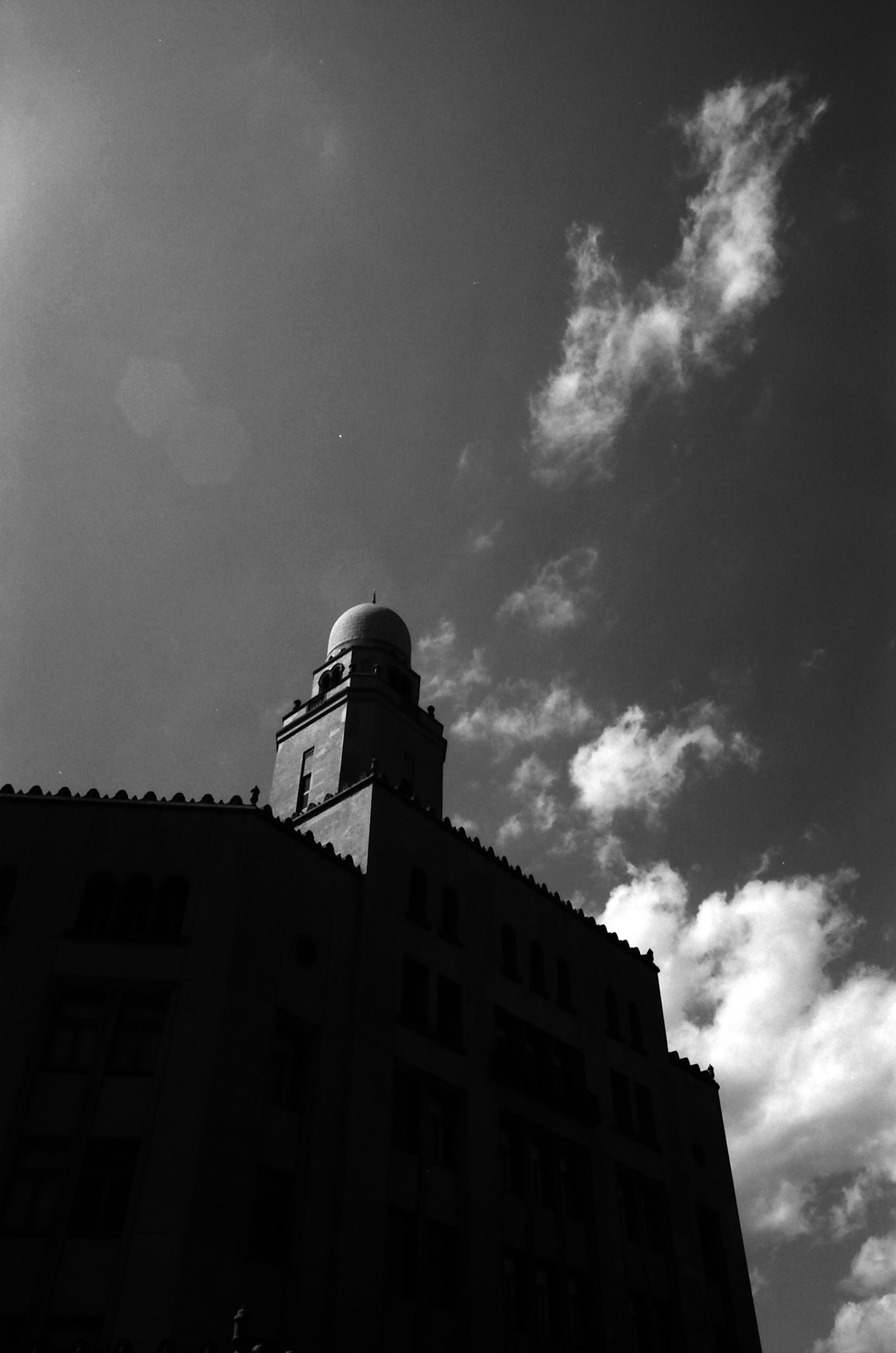 Silhouette of a tall building against a cloudy sky in black and white