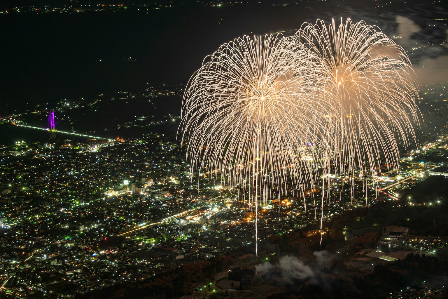Fuochi d'artificio che esplodono sopra una città di notte con luci brillanti
