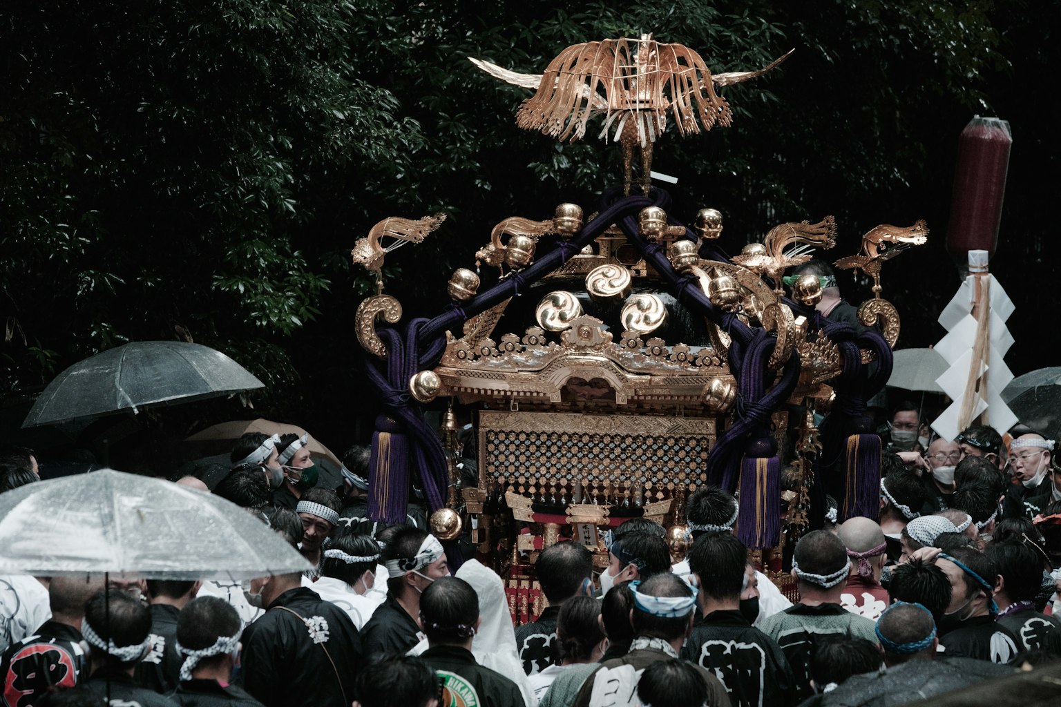 Crowd carrying a ceremonial palanquin with umbrellas in a festival