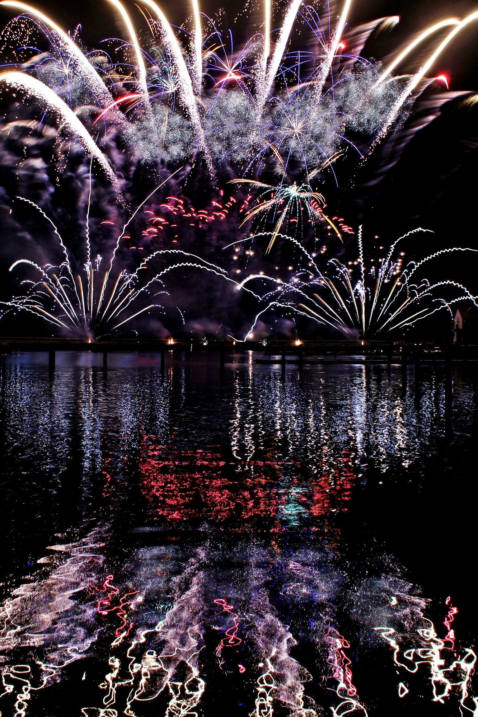 夜空中绽放的彩色烟花与水面上的美丽倒影
