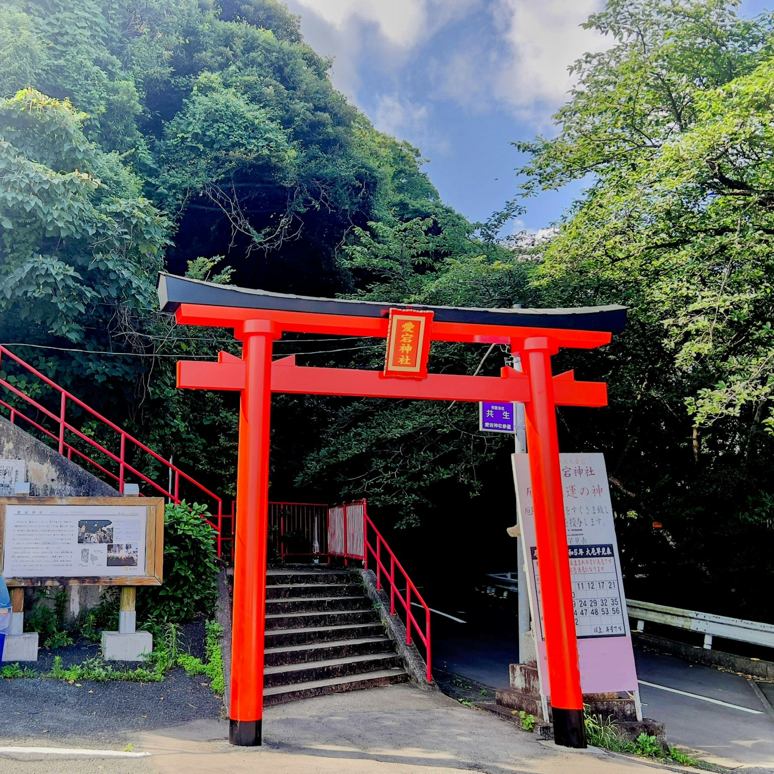 Rotes Torii mit Treppe umgeben von üppigem Grün am Eingang eines Schreins