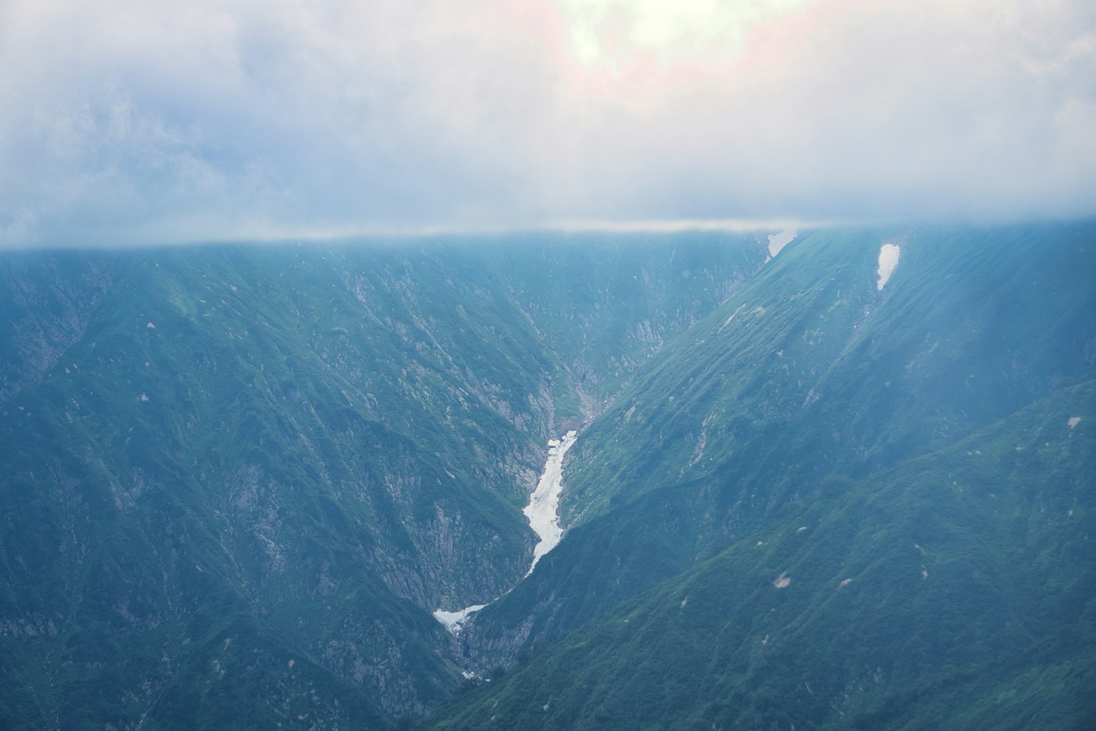 Paesaggio di montagne blu e canyon Cielo nuvoloso con neve che si scioglie e acqua che scorre
