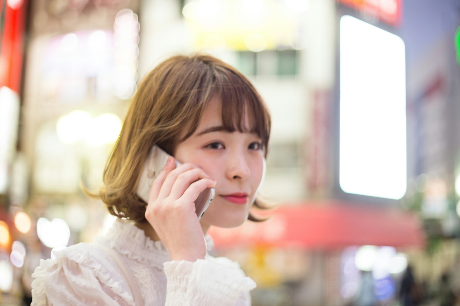Woman using smartphone in city lights