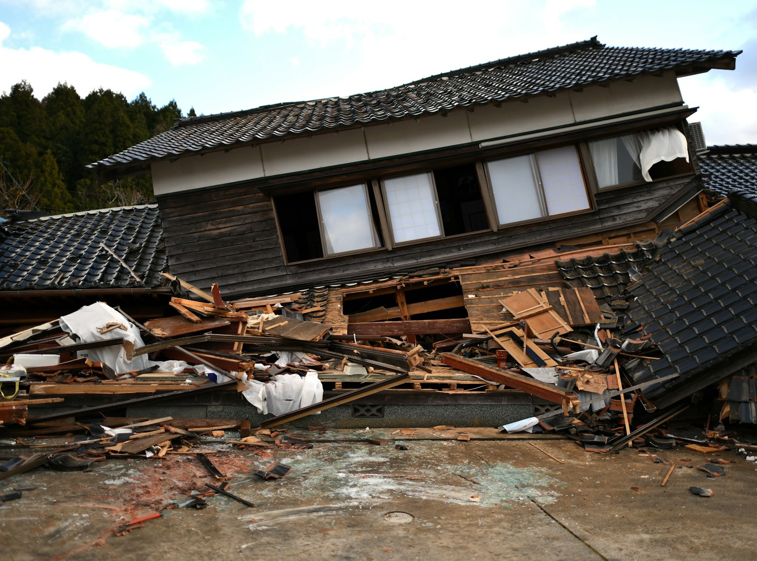 Eingestürztes japanisches Haus mit umliegenden Trümmern und Zerstörung
