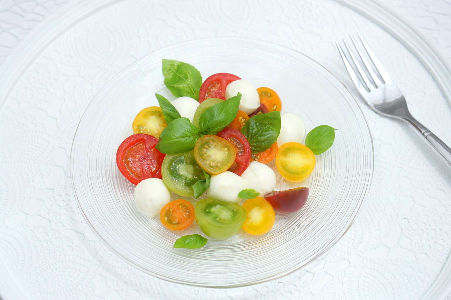 Ein buntersalat mit verschiedenen Tomaten und Mozzarellakugeln, garniert mit frischen Basilikumblättern