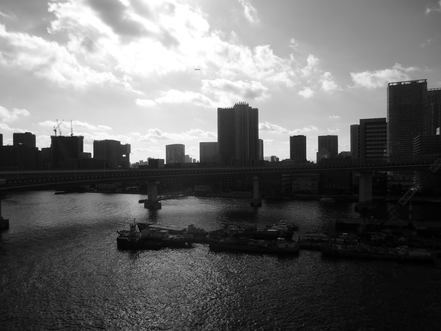 ภาพขาวดำที่จับภาพเส้นขอบฟ้าของโตเกียวและการสะท้อนในน้ำ