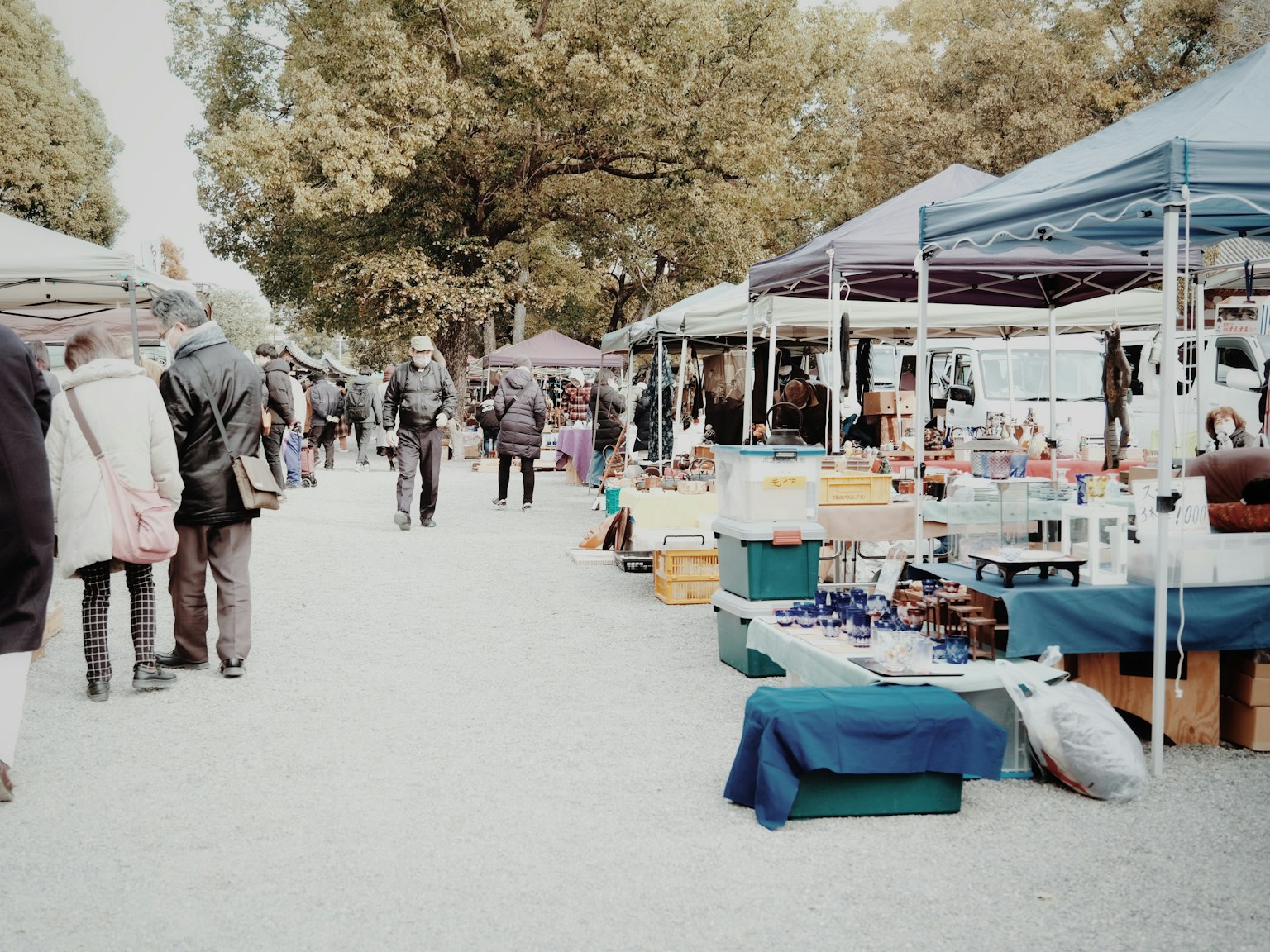 Scena di mercato all'aperto con persone che camminano tende e vari beni esposti