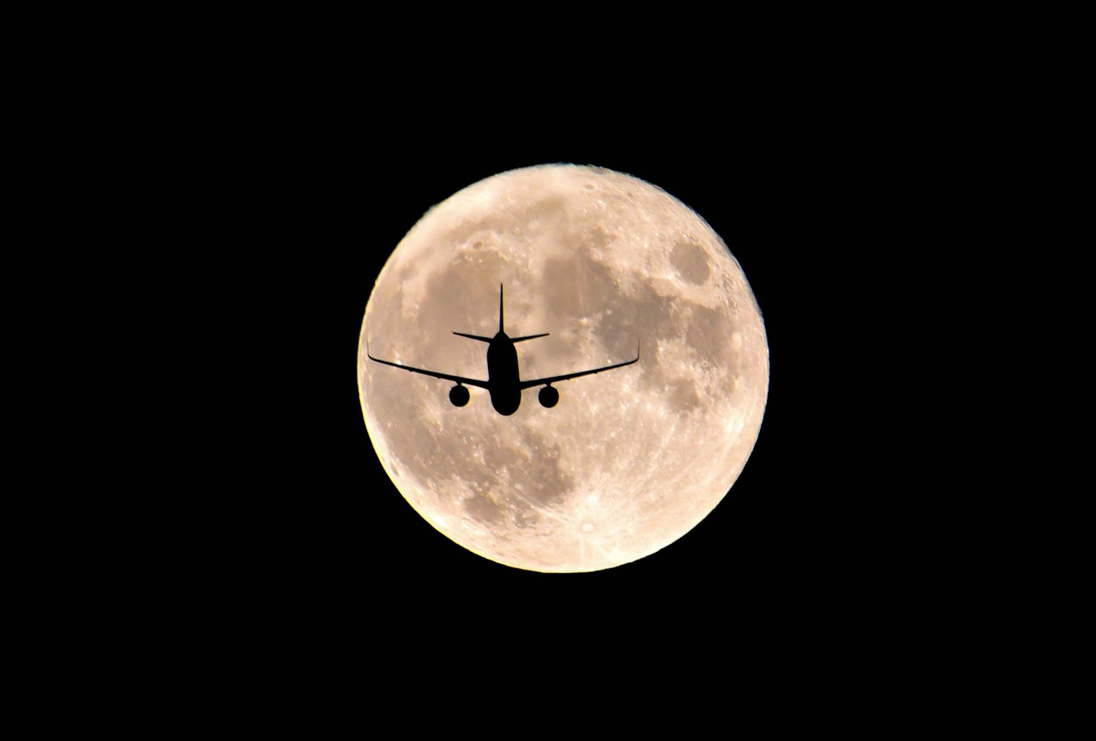 Silhouette eines Flugzeugs, das vor dem Mond fliegt