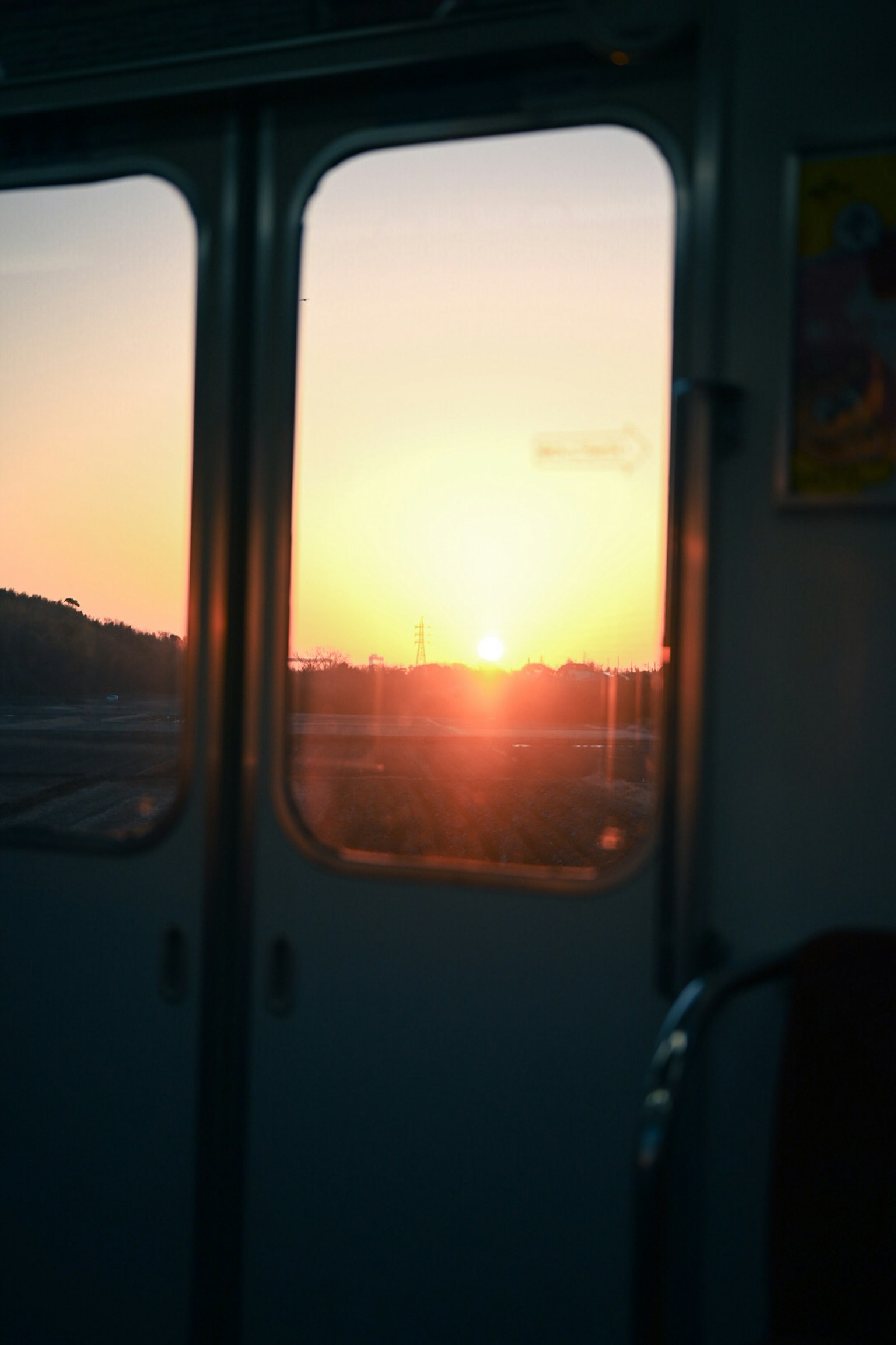 Vista del atardecer desde una ventana de tren con siluetas de colinas