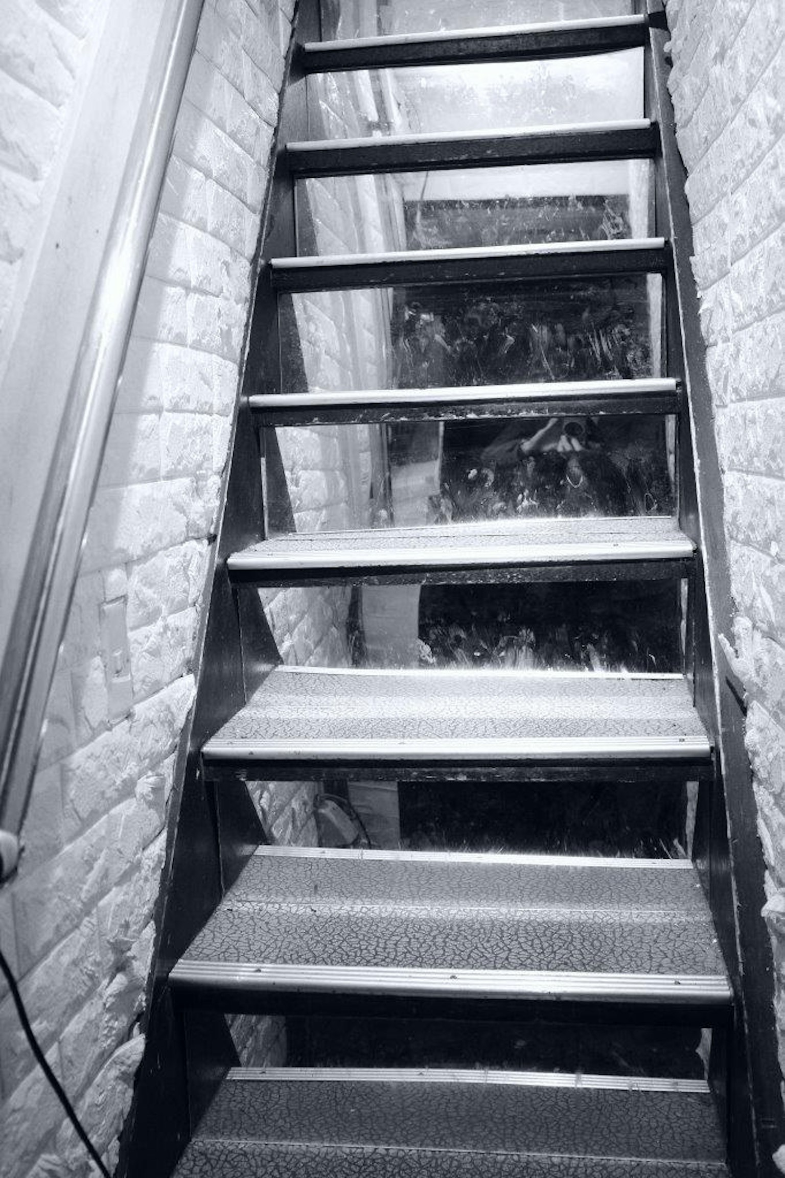 Image d'un escalier vu d'en haut dans un environnement faiblement éclairé avec des marches en métal