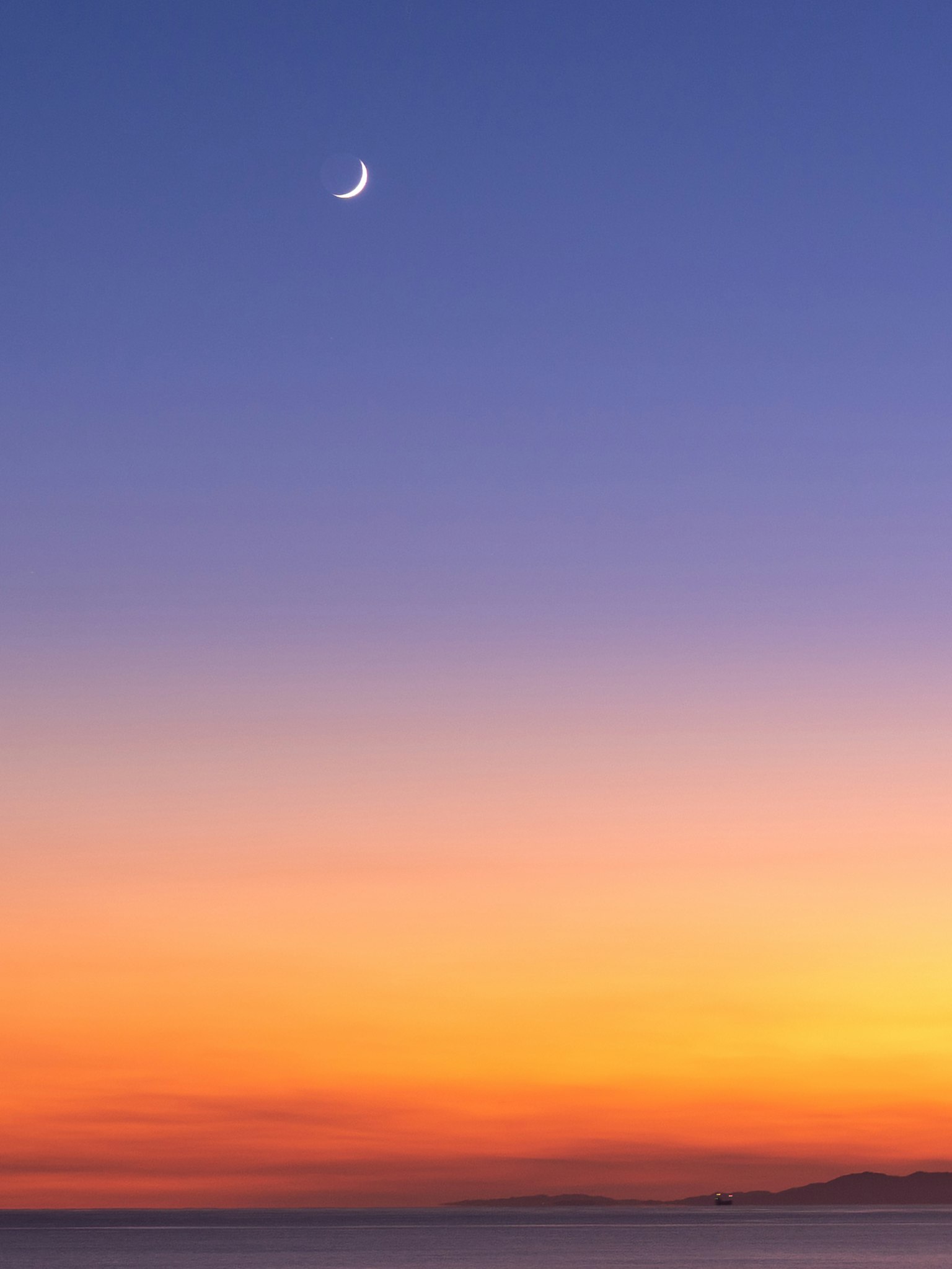 Schöner Sonnenuntergang mit einem zunehmenden Mond im Himmel