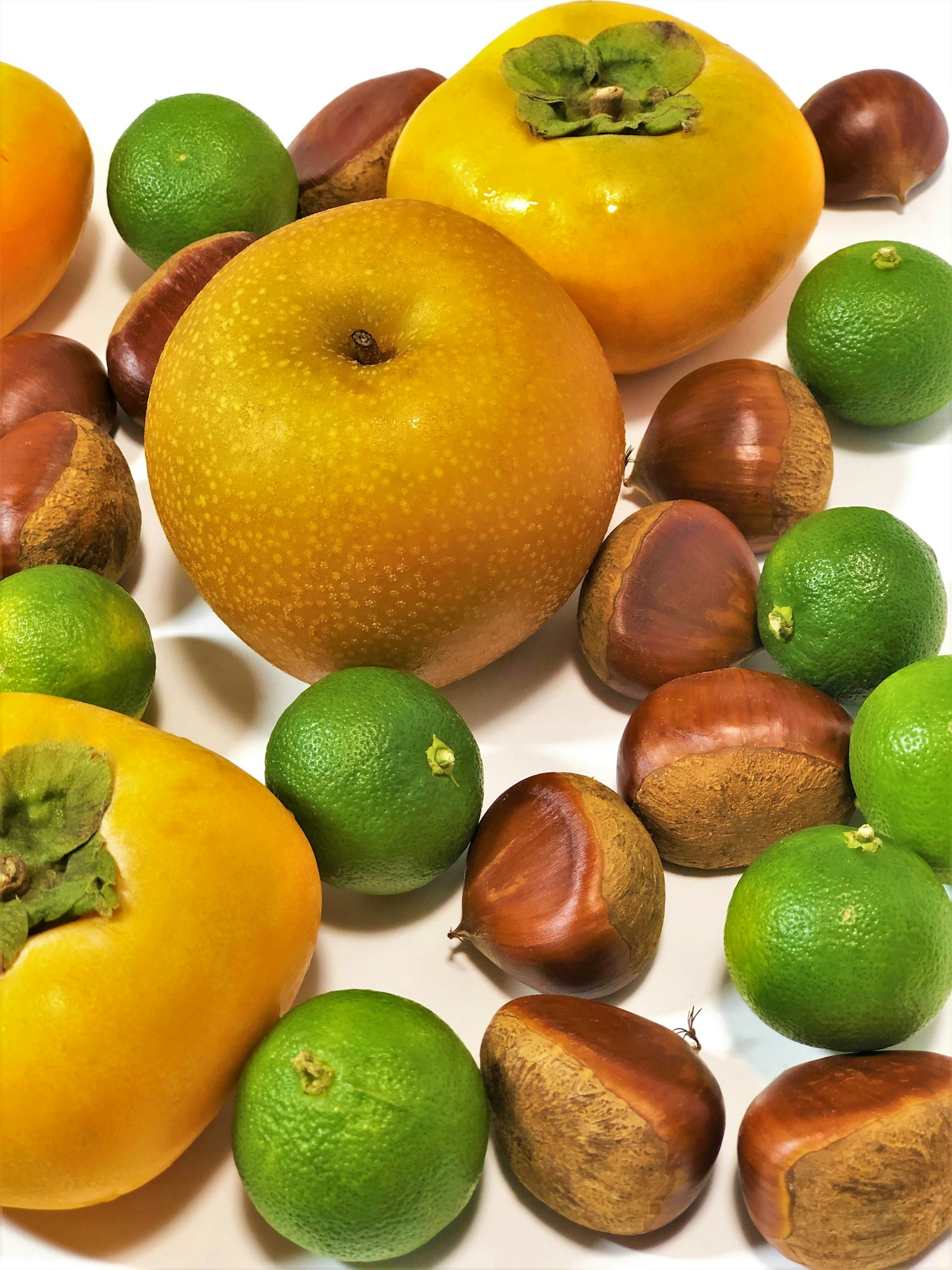 Bunte Anordnung von Früchten und Nüssen einschließlich Kakis und Kastanien