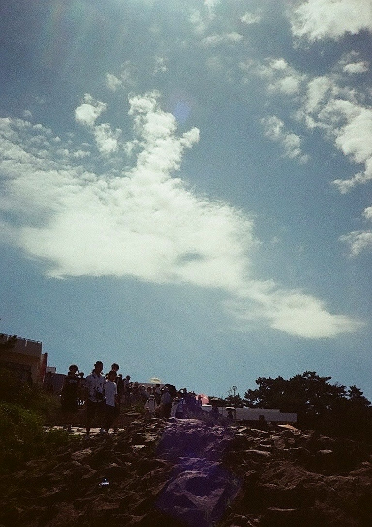 People gathered on a rocky slope under a bright blue sky