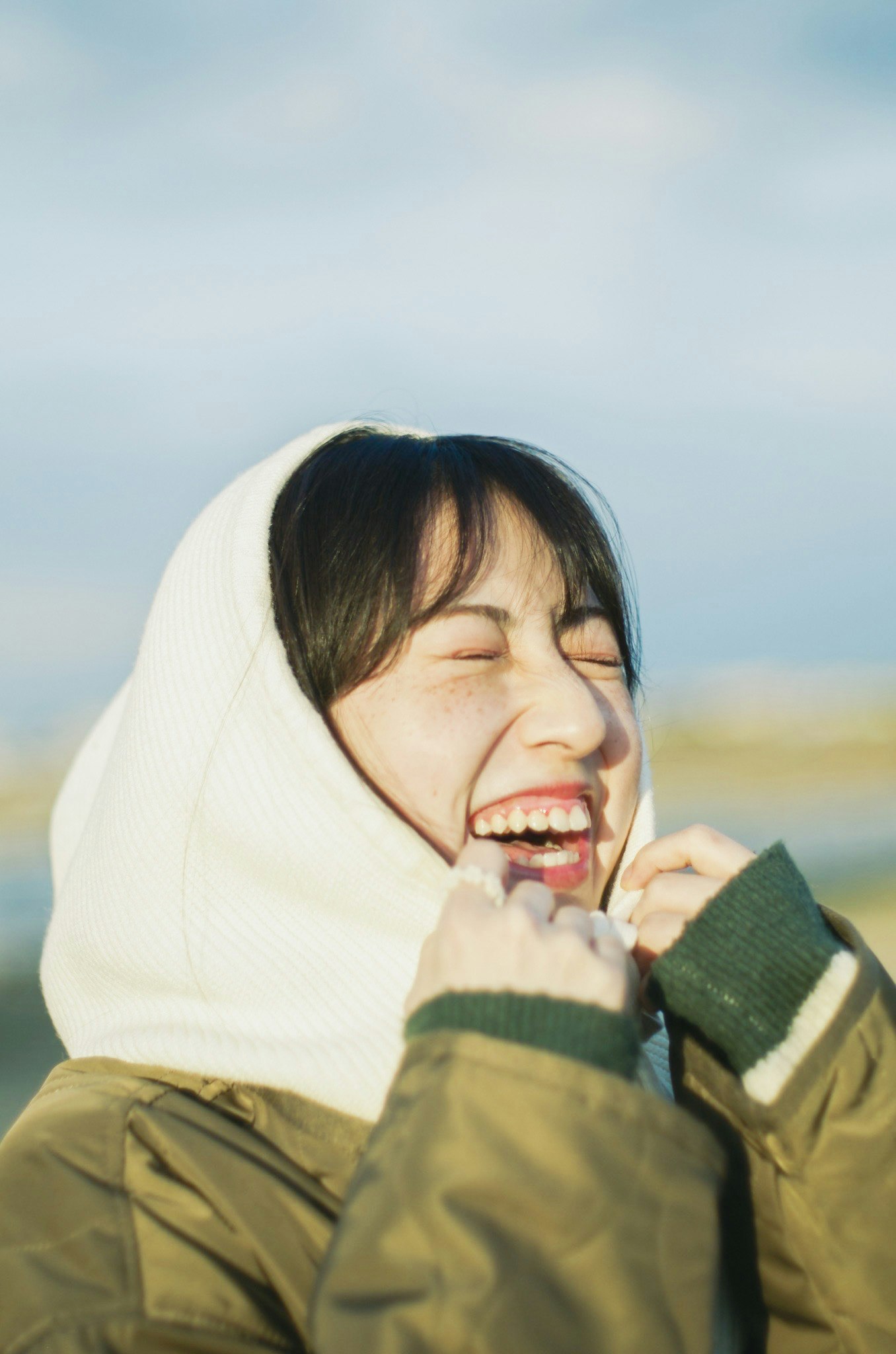 笑顔で頬を寄せるフード付きコートの女性