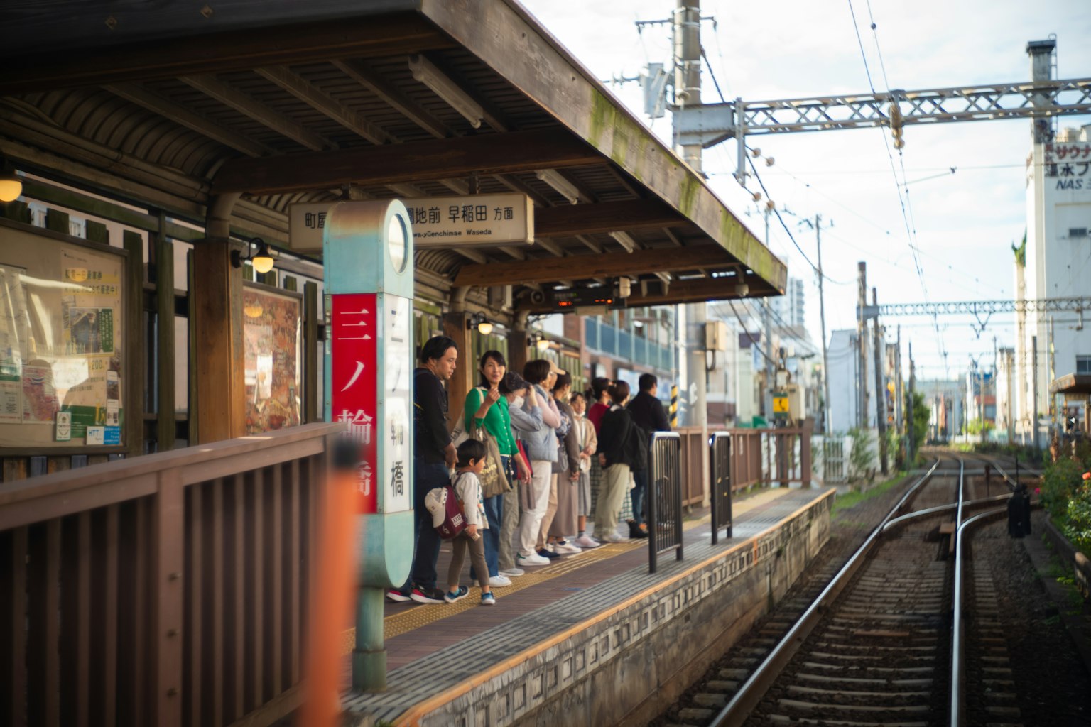 Personas de pie en una plataforma de tren con vías visibles
