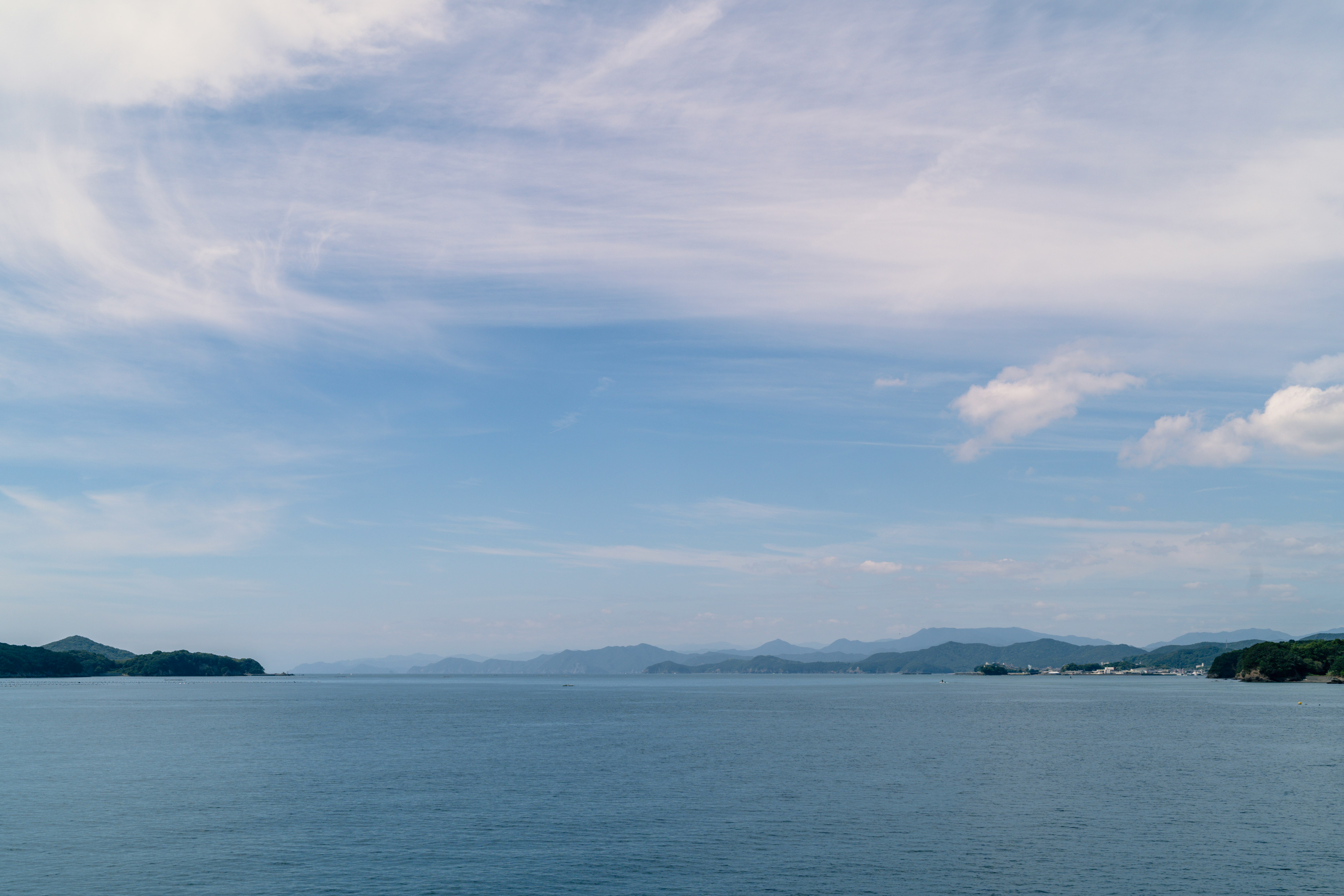 穏やかな海と遠くの山並みが広がる水平線の風景