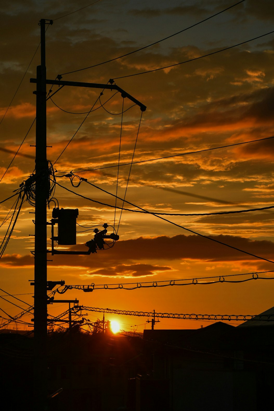 夕焼け空に伸びる電線と街灯のシルエット