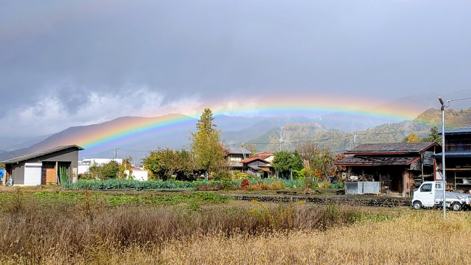 山々の上にかかる虹と田舎の風景が広がる風景