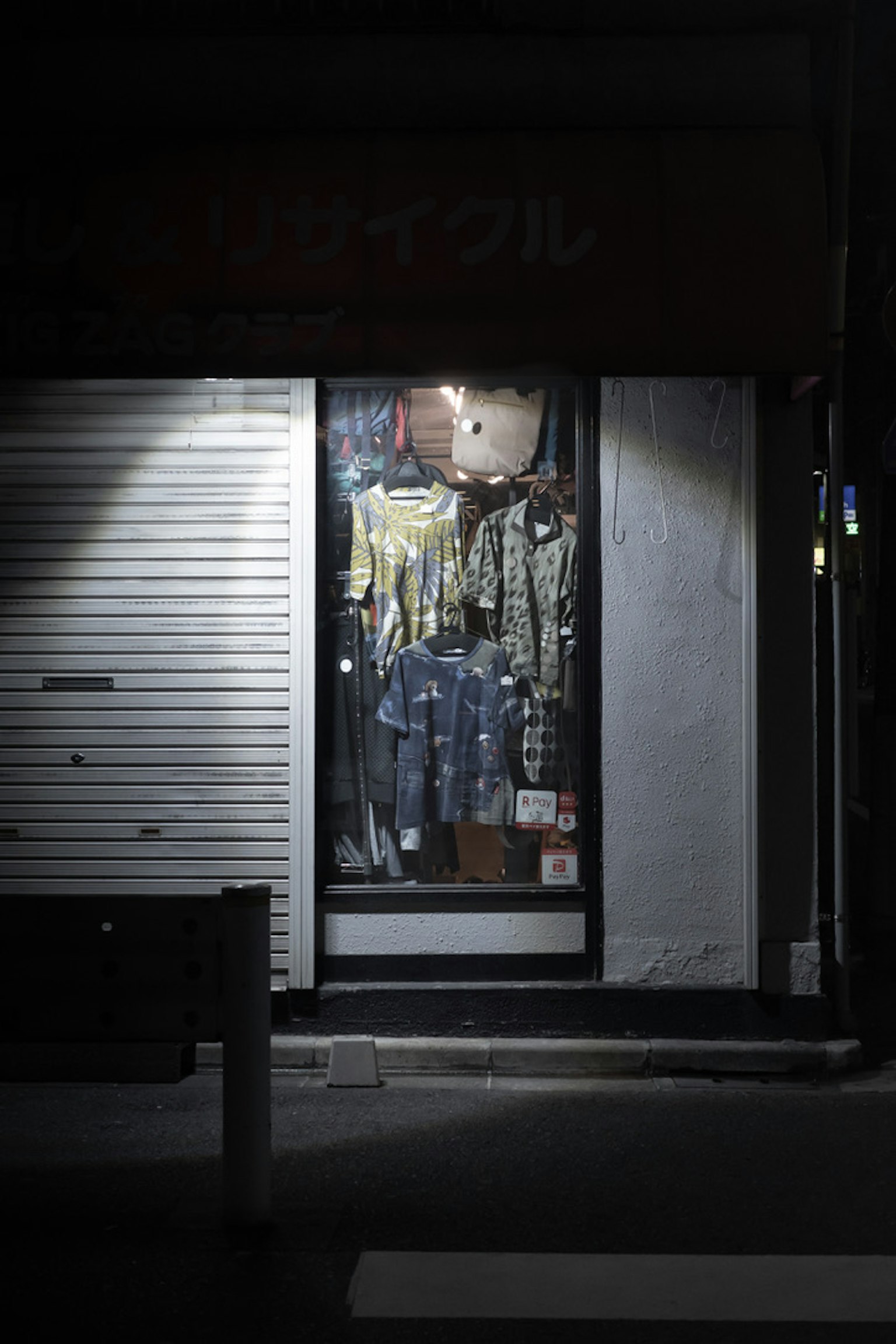 Ropa y mercancía exhibidas en una vitrina de tienda por la noche