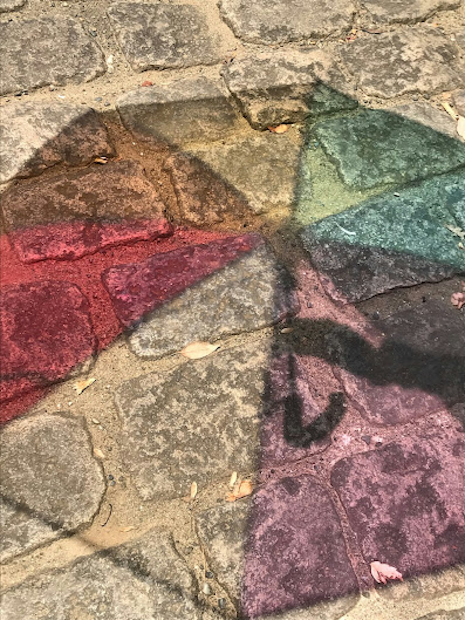 彩色雨傘的陰影在鵝卵石路面上