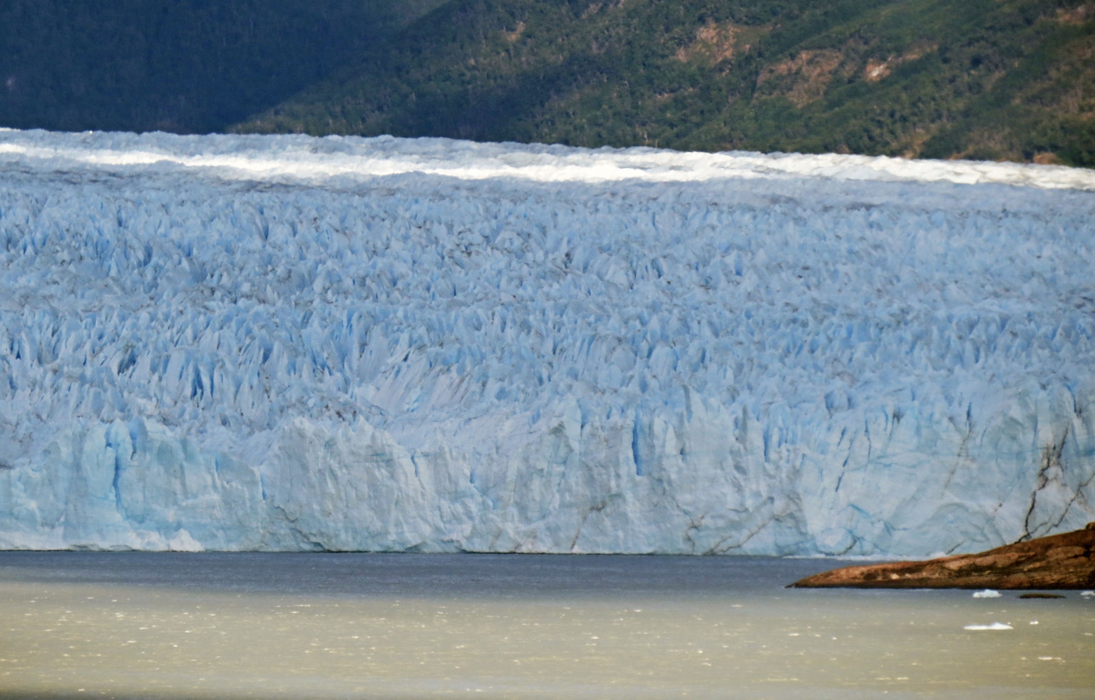 Mur majestueux de glacier bleu se reflétant sur la surface de l'eau