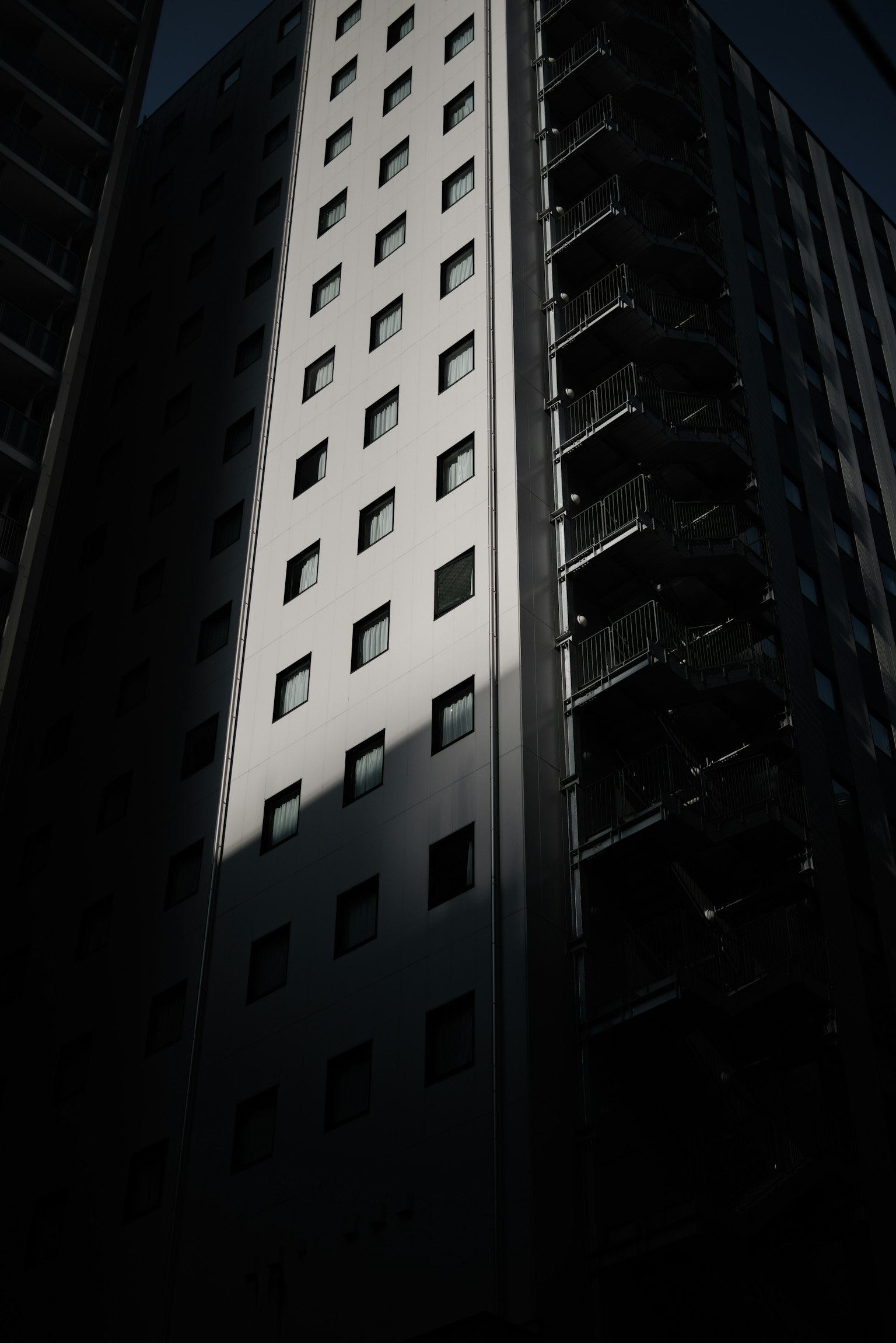 Side view of a high-rise building against a dark background striking contrast of light and shadow