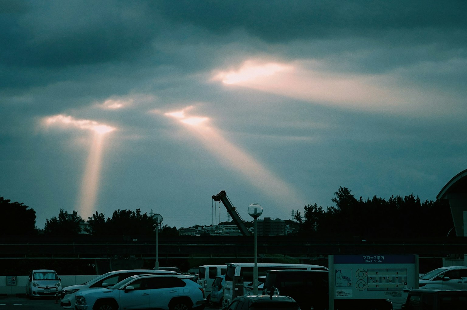Lichtstrahlen, die durch dunkle Wolken brechen, mit umliegenden Fahrzeugen