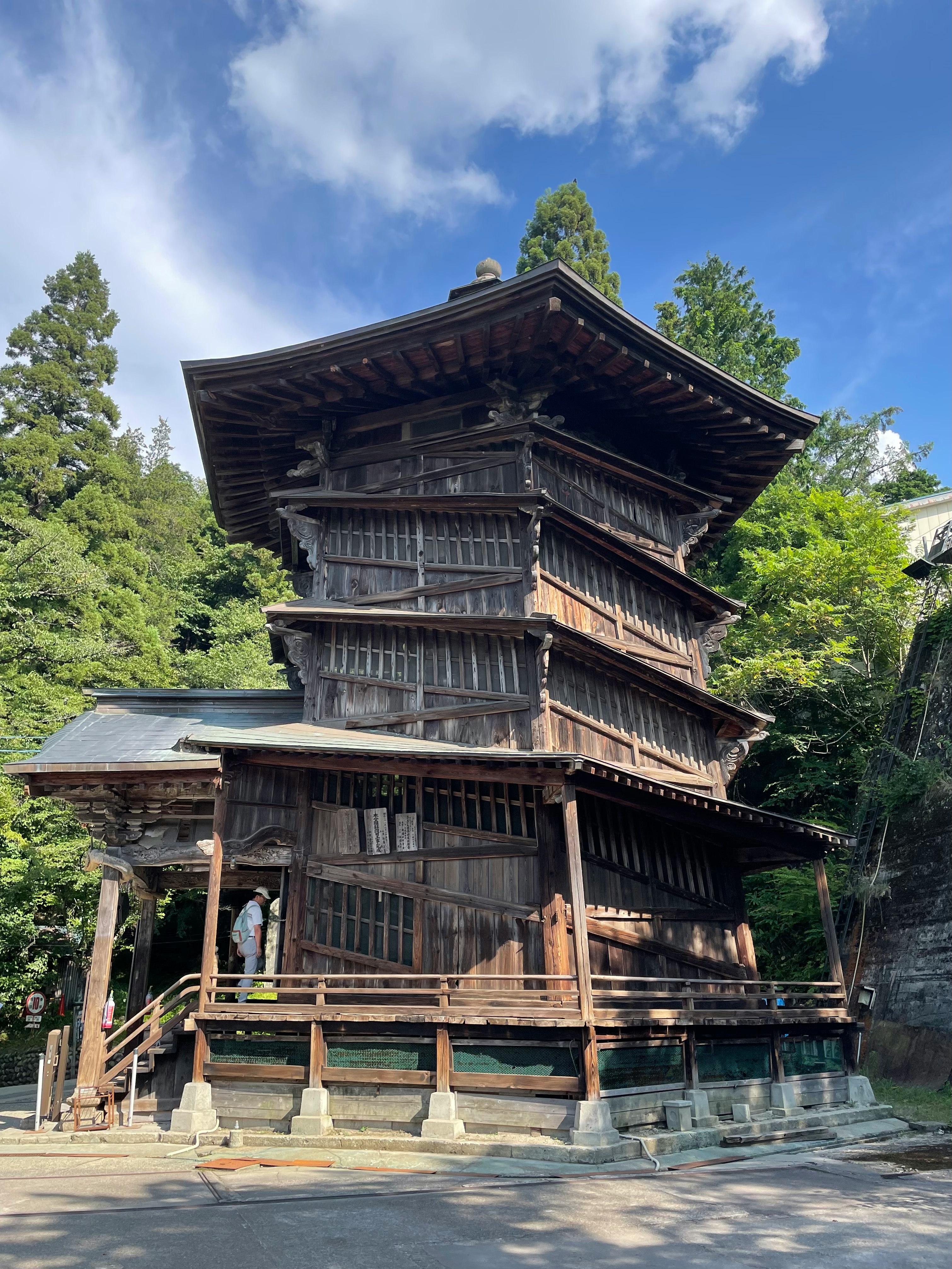 木造の多層建築と周囲の緑に囲まれた寺院の外観