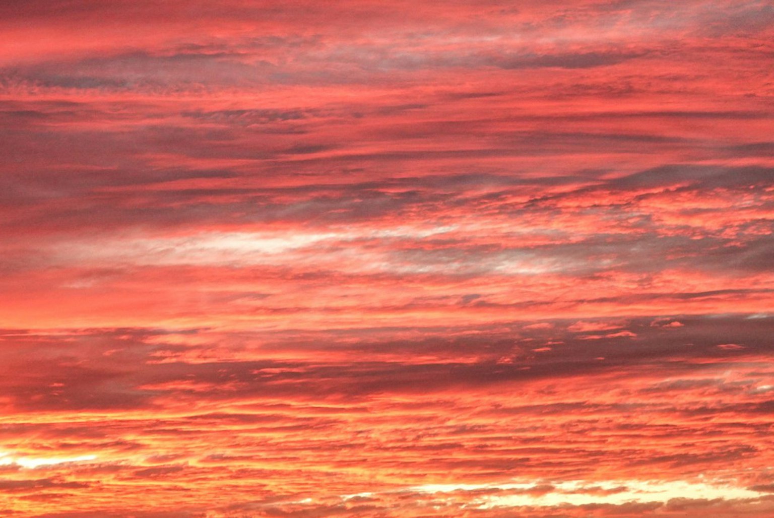 Langit senja yang cerah dengan lapisan awan merah dan oranye